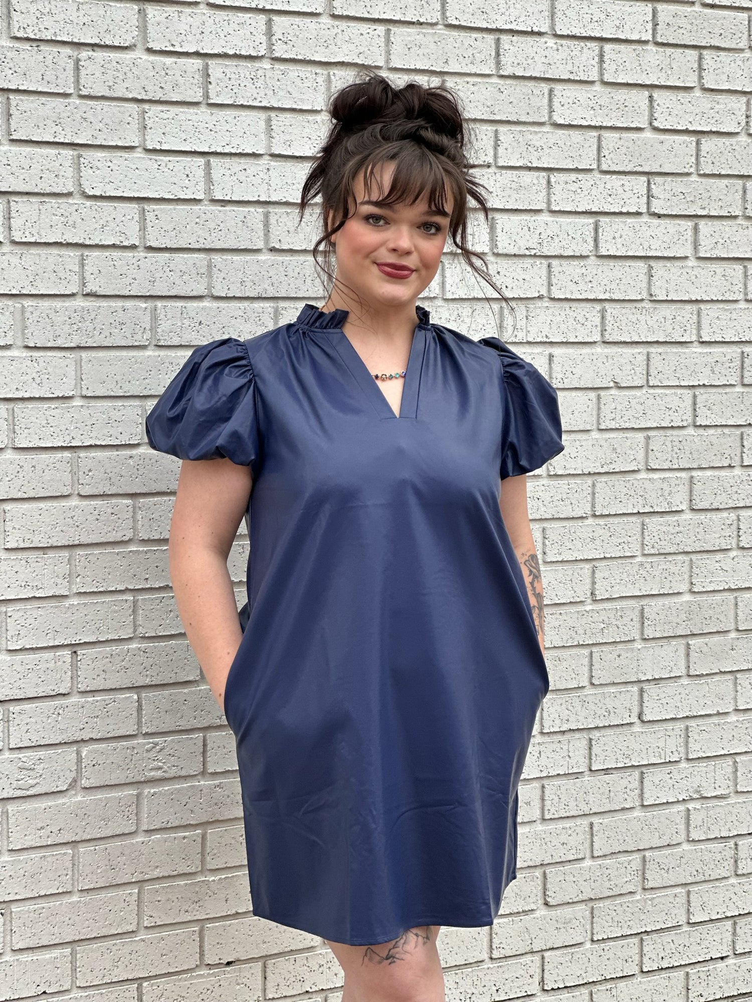 GIRL WEARING BLUE DRESS STANDING BY BRICK WALL